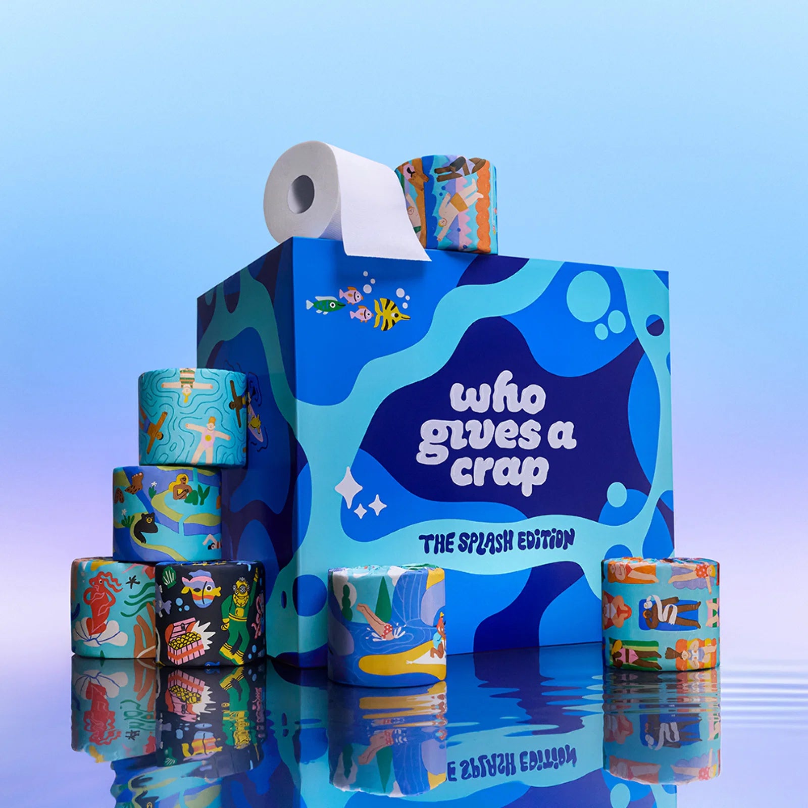 The Who Gives A Crap Splash Edition box and illustrated bamboo toilet rolls reflected in water, with a collection of uniquely designed rolls on display